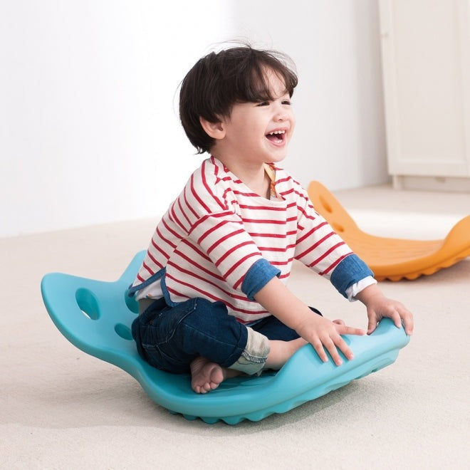 Weplay Whally Board Blue balance toy for toddlers; blue wobble board with child sitting and smiling.