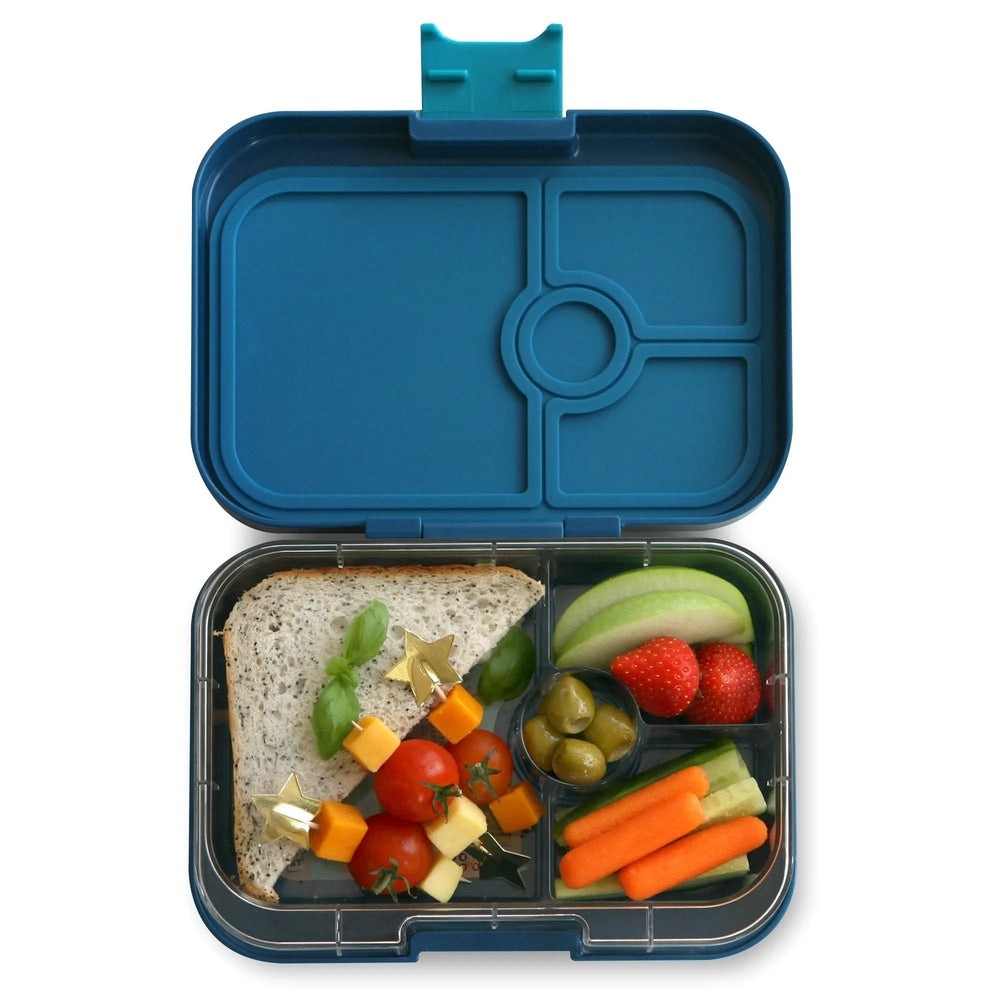 Yumbox Panino 4-compartment blue lunchbox open to reveal sandwich, olives, carrot sticks, cucumber, and fruit.