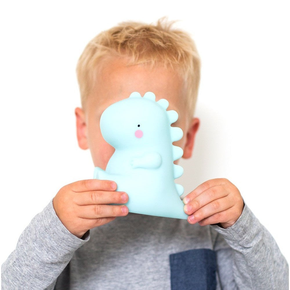 A Little Lovely Company Little Night Light T-Rex in soft blue silicone, being held by a child.