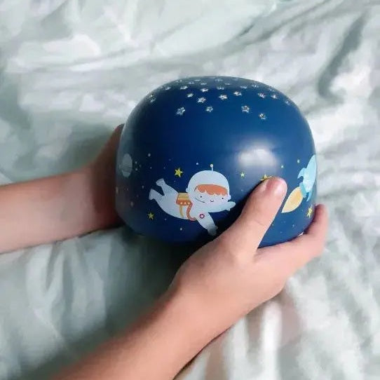A Little Lovely Company Projector Night Light, blue sphere held by child, showcasing star projection.