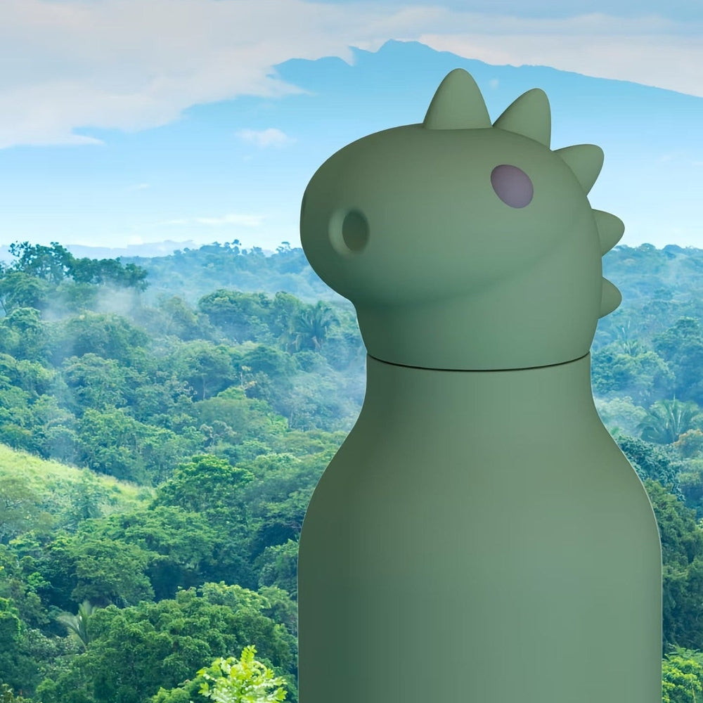 ASOBU Bestie Animal Dinosaur 16oz double-wall stainless steel bottle held upright in a tropical jungle scene