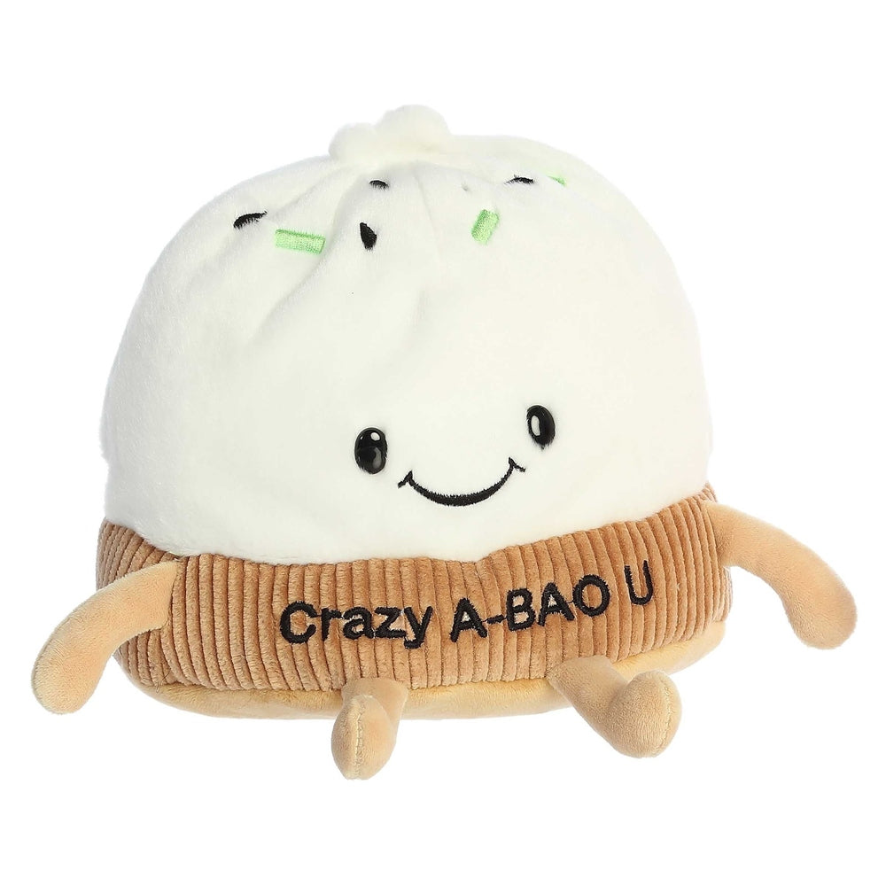 White plush bao bun with brown ribbed wrapper, embroidered 'Crazy A-BAO U', tiny arms and legs, and a smiling face.