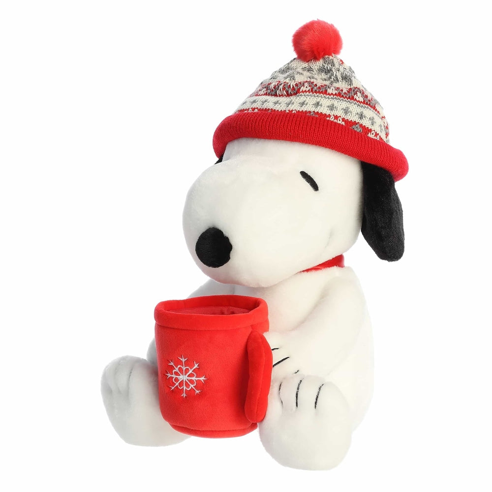 Snoopy plush stuffed animal by Aurora in a red knit winter hat with pom, holding a red mug