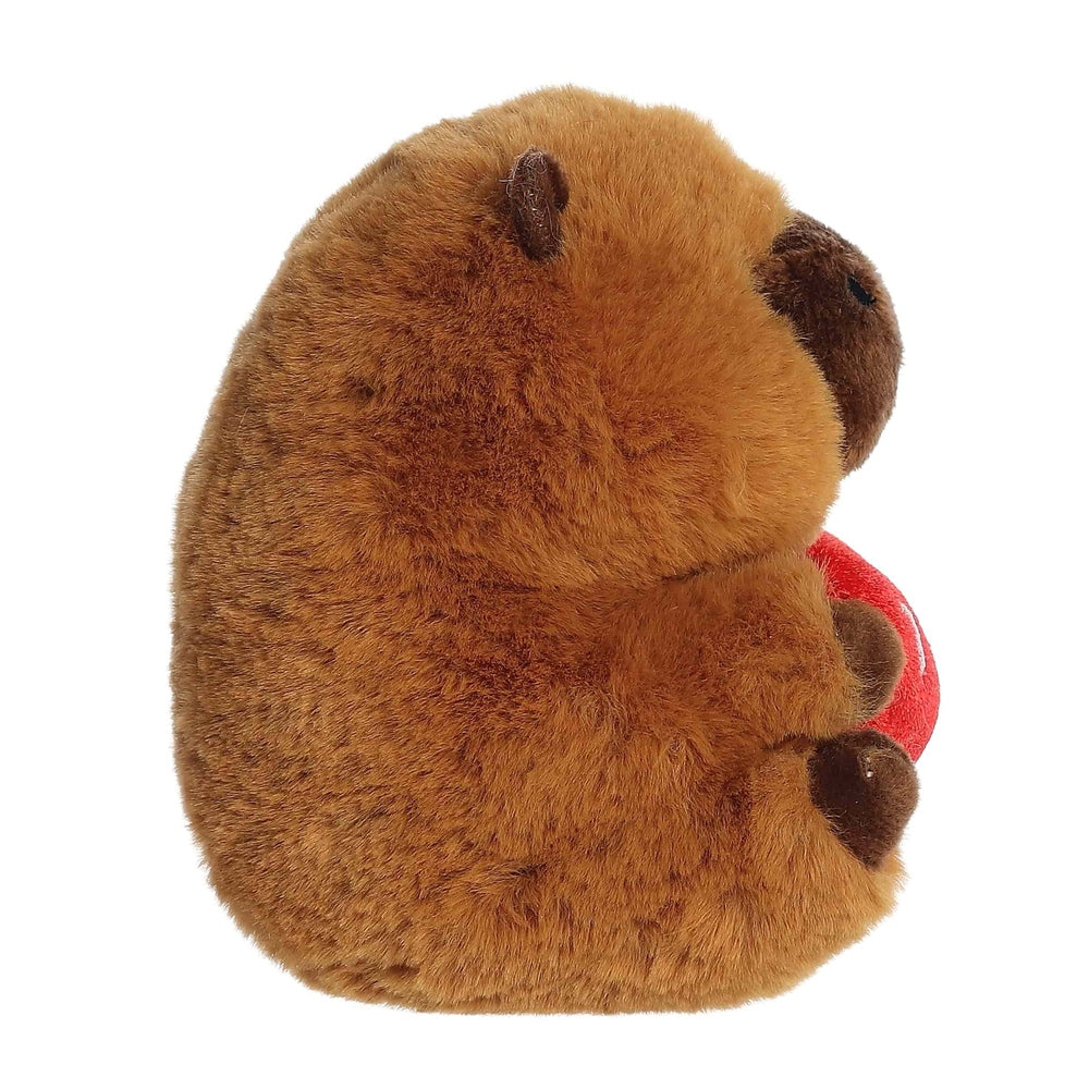 Brown plush capybara stuffed animal with soft fur and dark nose, holding a red ball.