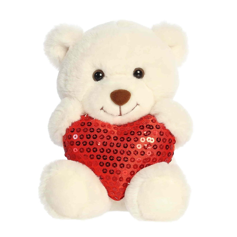 Cream plush bear with a red sequin heart on its chest, friendly face.