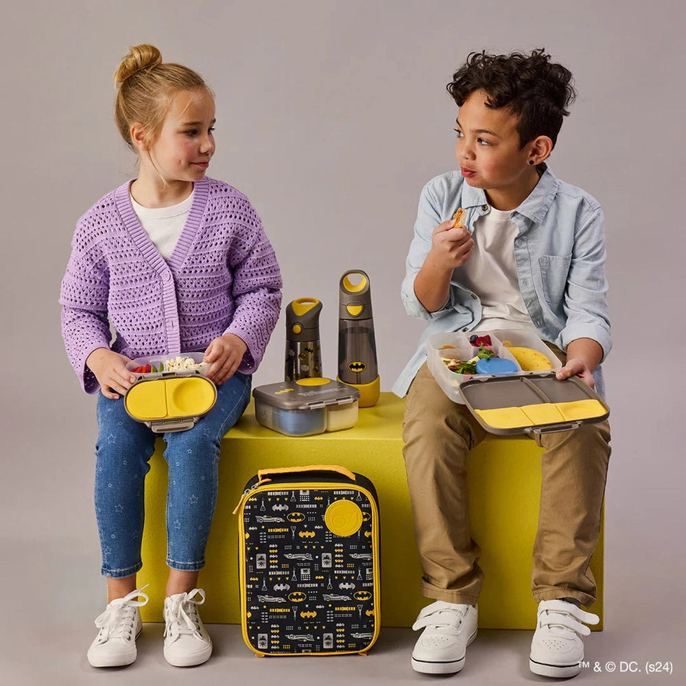 B.BOX Insulated Flexi Lunchbag with Batman print; two kids eat from colorful trays beside the insulated bag.