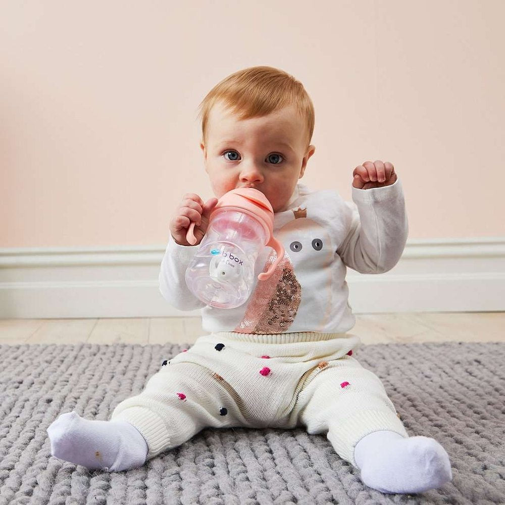B.Box New Sippy Cup Gelato Edition clear bottle with pink lid, held by a baby