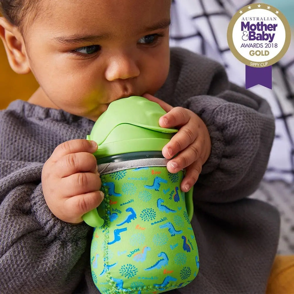 B.Box New Sippy Cup Matte Edition lime green cup with blue sleeve; baby grips it and sips from the lid.