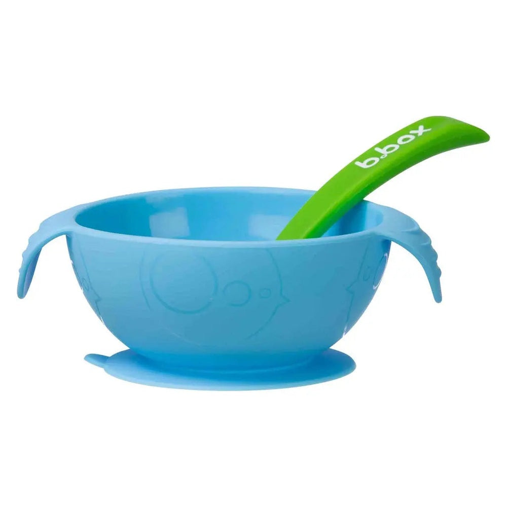 B.Box Silicone First Feeding Set blue suction bowl with green spoon positioned inside for mess-free feeding.