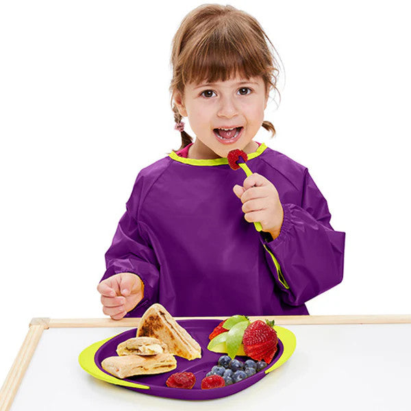 B.Box Smock Bib Large Passion Splash purple bib with lime trim on a child at snack time.
