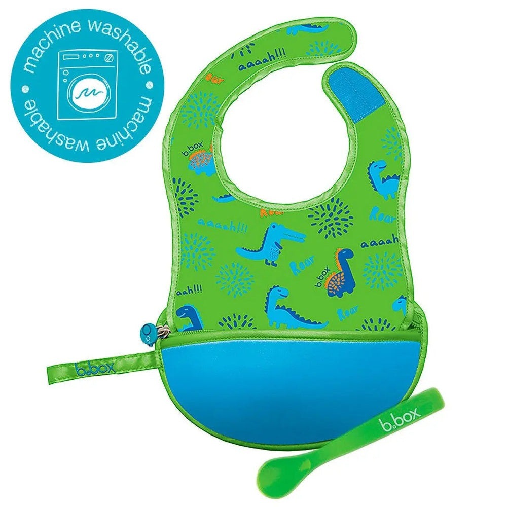 B.Box Travel Bib for babies, green with blue pocket and dinosaur print, includes spoon and machine-washable badge.