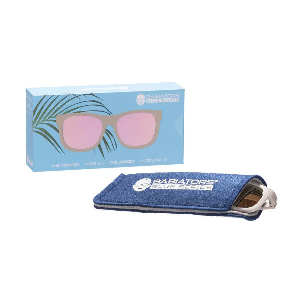 Babiators Blue Series Navigator polarized sunglasses in warm grey tucked into a blue microfiber sleeve beside the box.