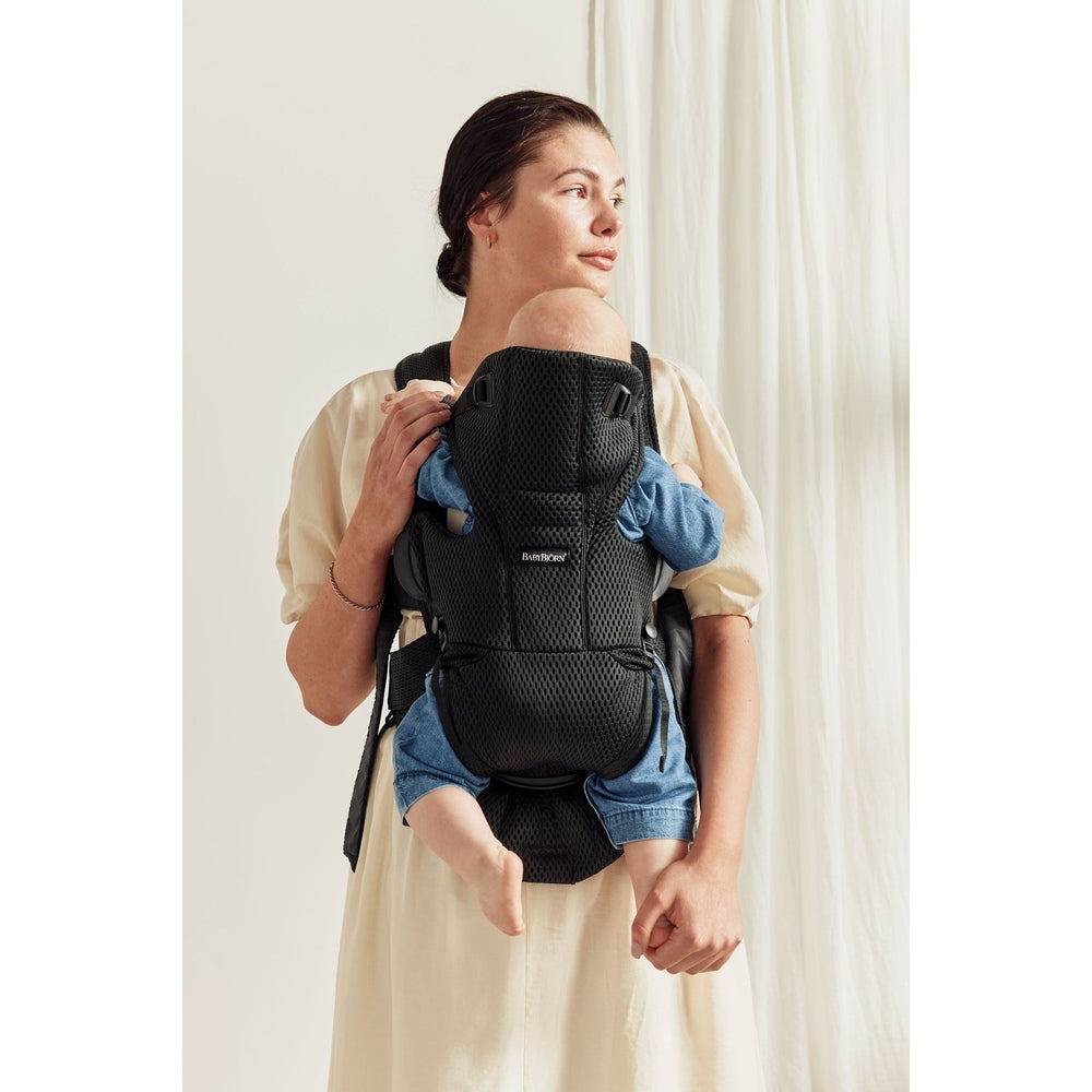 BabyBjorn Baby Carrier Free in black mesh worn by mom with baby snug against her chest, hands-free support.