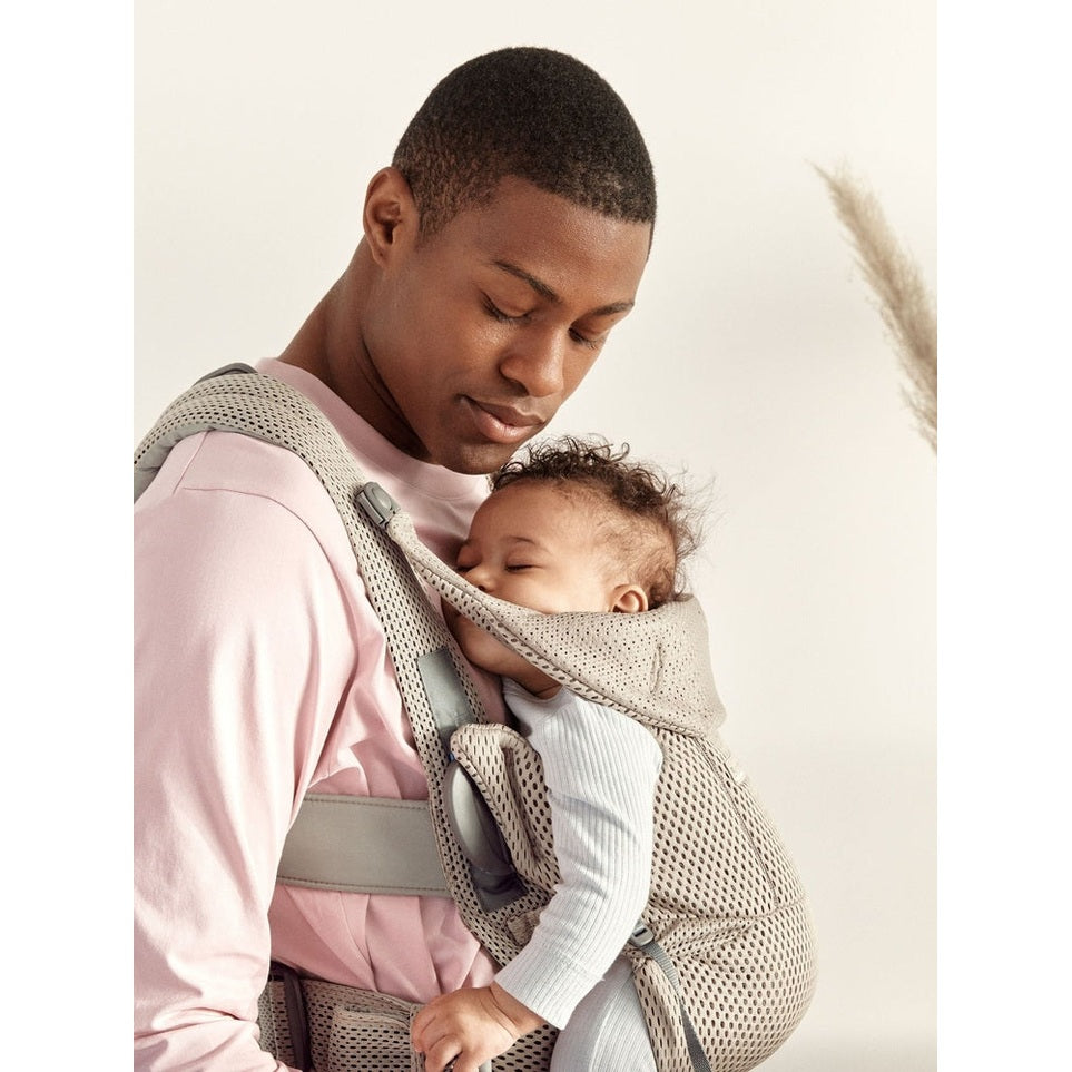 BabyBjorn Baby Carrier Free worn by a father with a sleeping baby in a beige breathable mesh carrier.