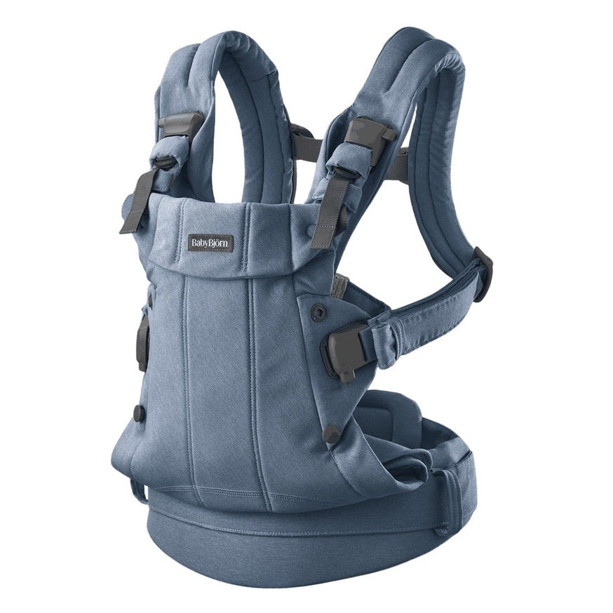 BabyBjorn Baby Carrier Harmony in blue, worn by caregiver, showing padded straps and secure adjustable buckles.