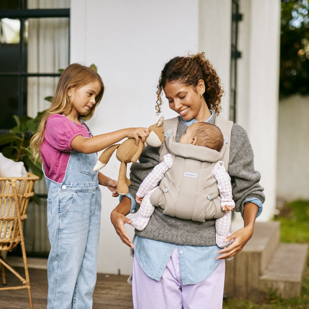BabyBjörn Baby Carrier Hold in Brushed Woven Sand Gray - parent carrying baby inward outdoors