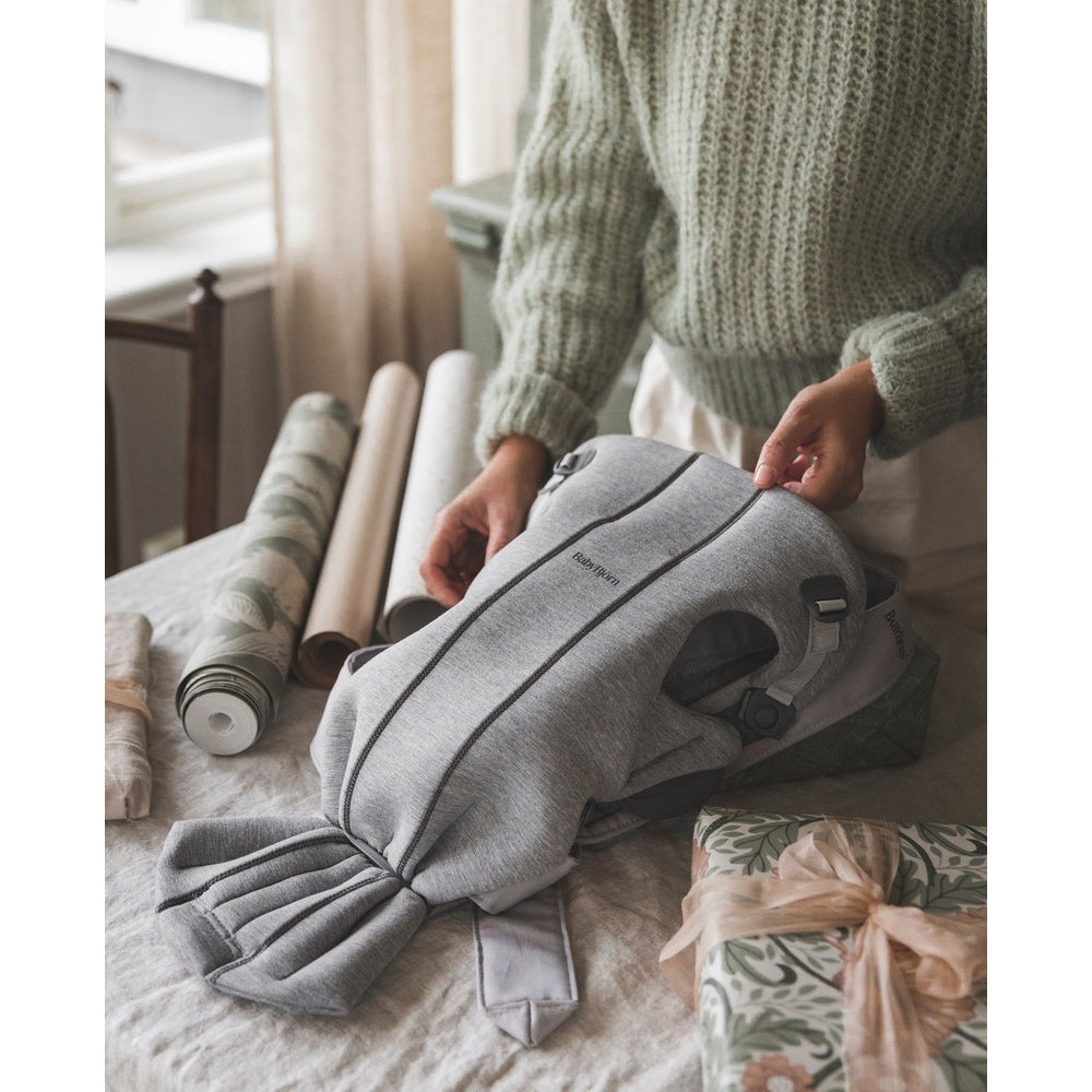 BABY BJORN Baby Carrier Mini in gray, being unpacked on a table to reveal its compact ergonomic design.