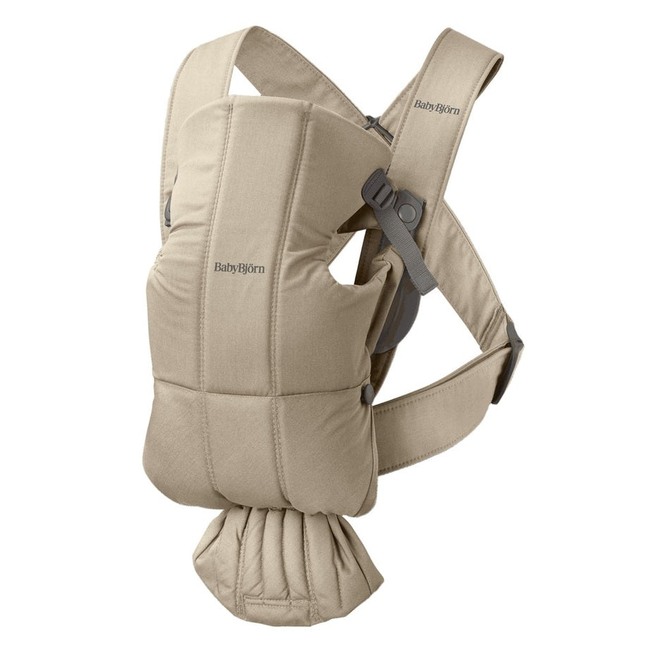 BabyBjorn Baby Carrier Mini beige worn by a parent, showing padded straps and adjustable buckles.