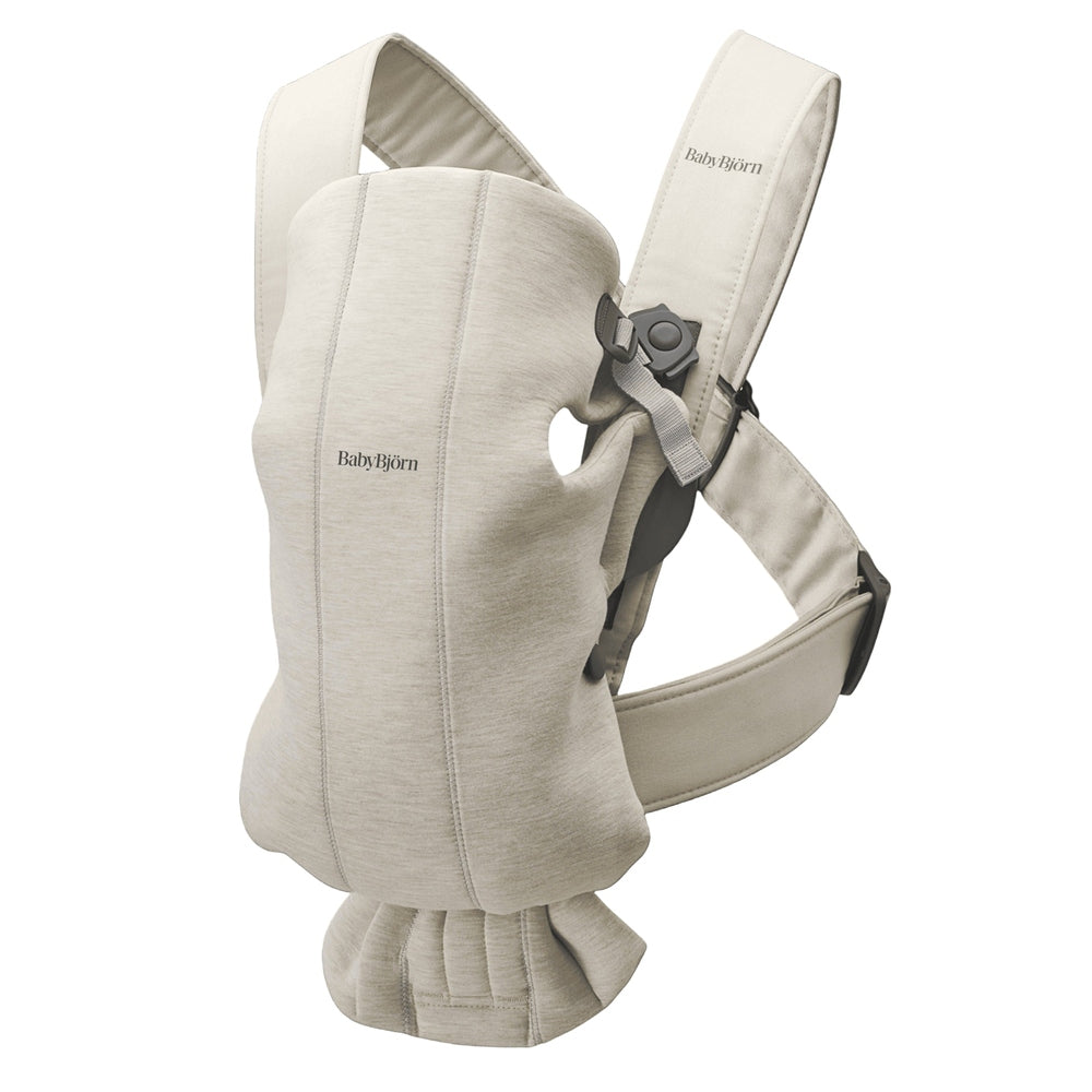 BabyBjorn Baby Carrier Mini in beige worn by parent, with padded shoulder straps and secure waist belt.