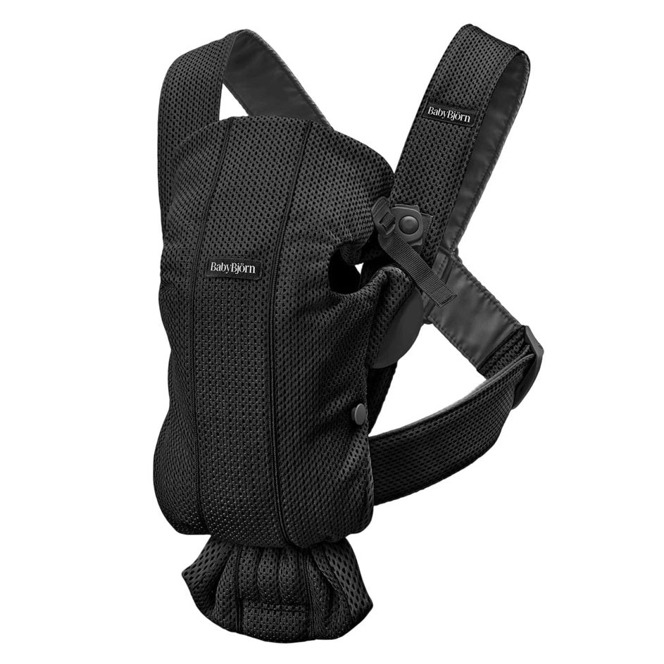 BabyBjorn Baby Carrier Mini in black mesh, worn by a parent with padded, adjustable straps for support.