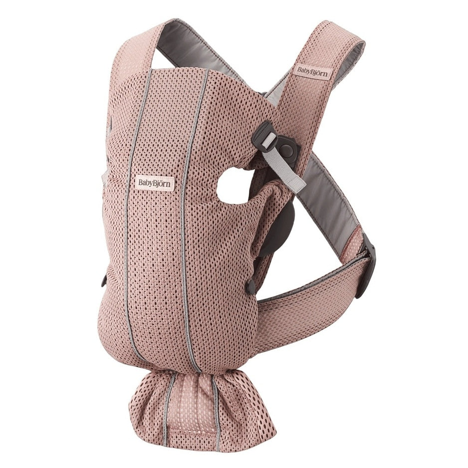 BabyBjorn Baby Carrier Mini in pink mesh worn by parent, showcasing adjustable straps and supportive waist belt.