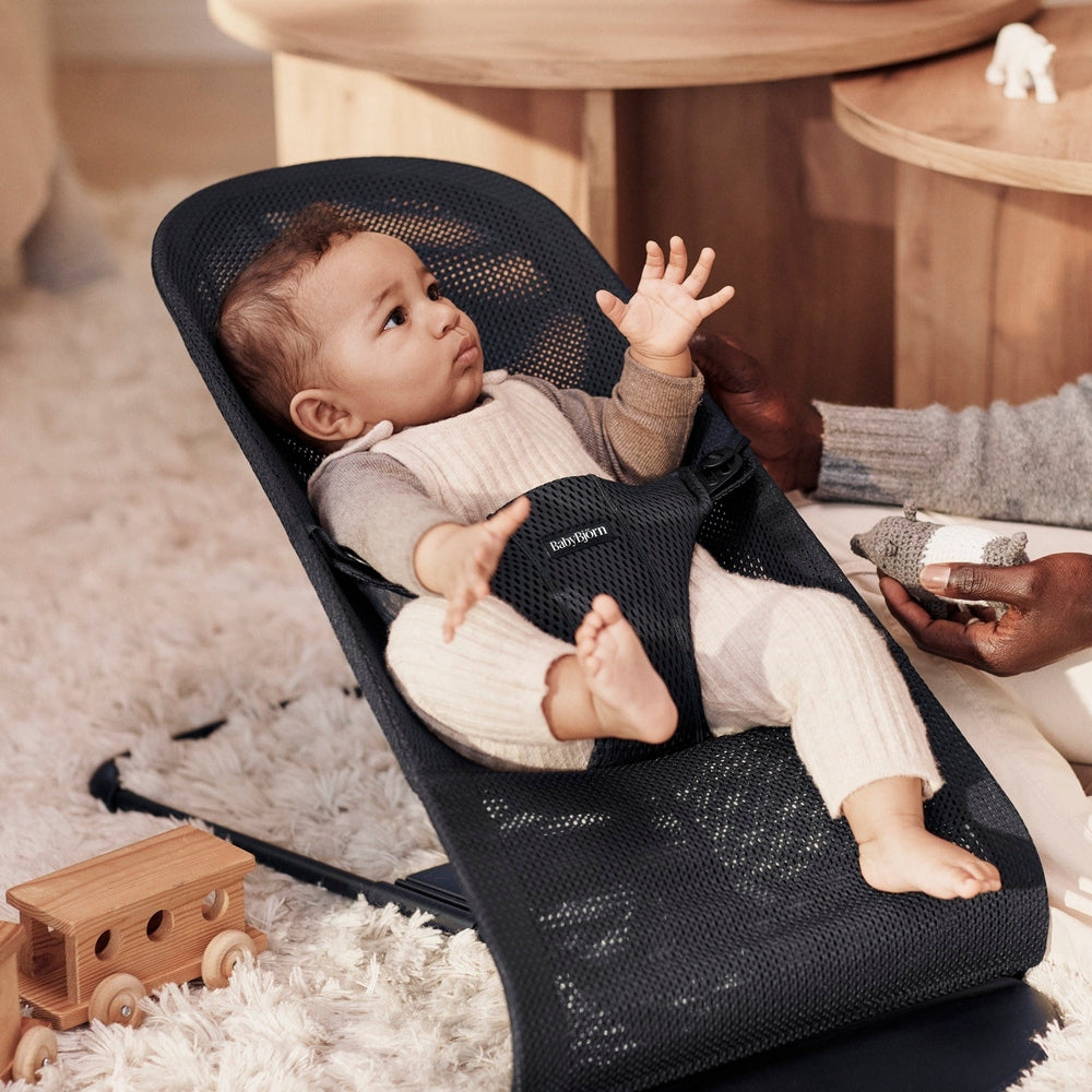BabyBjorn Bouncer Bliss Black Mesh in use as a baby reaches up, showcasing breathable mesh and ergonomic support.