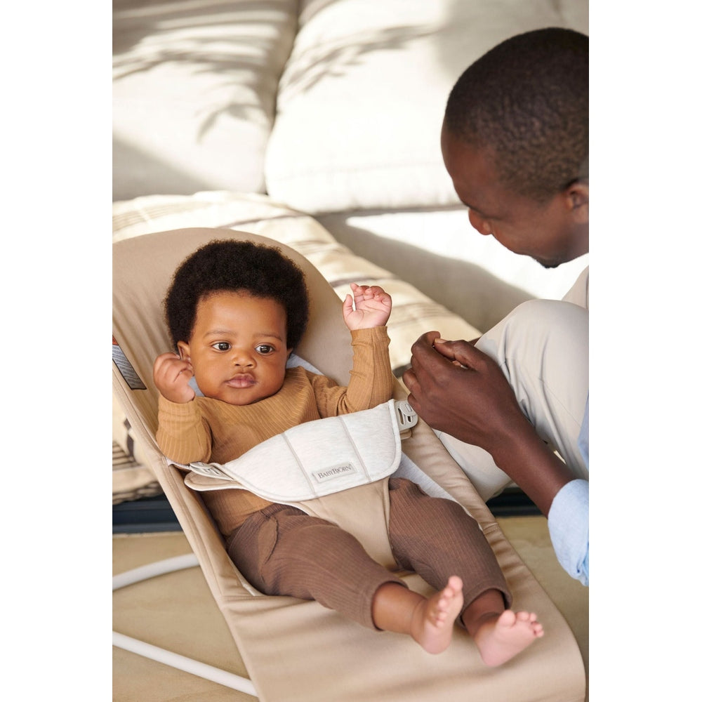 BabyBjorn Bouncer Bliss in beige, parent adjusting the harness as baby sits calmly in the seat.