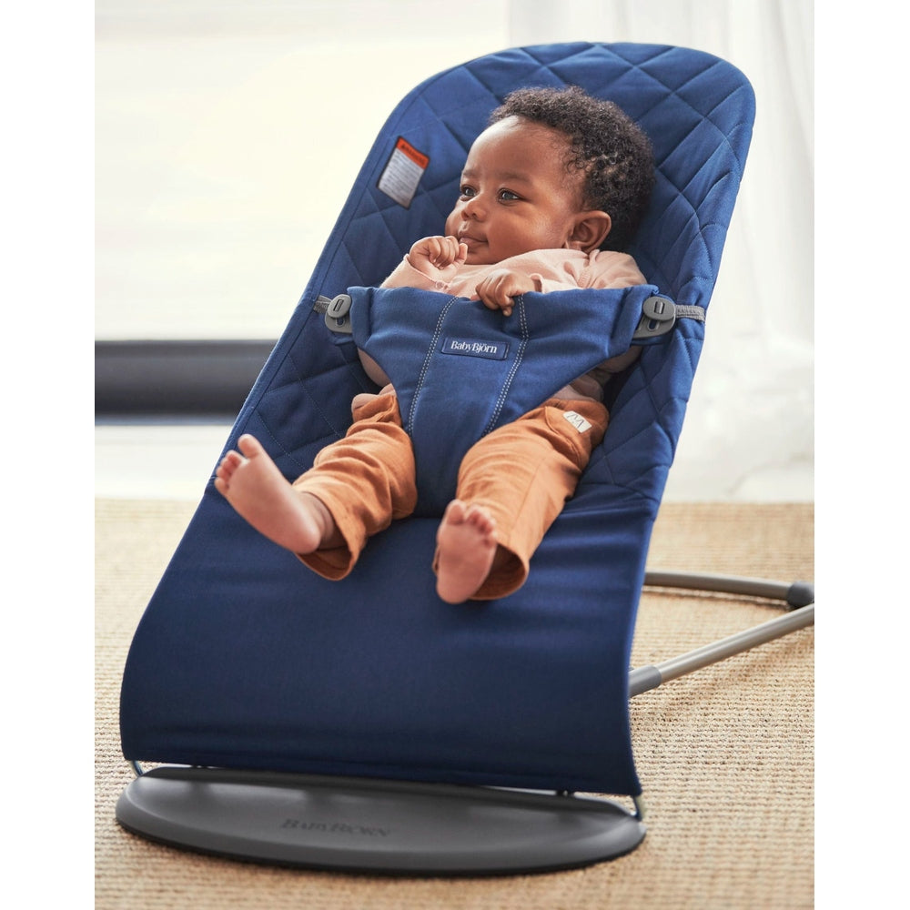 BabyBjorn Bouncer Bliss in navy blue fabric; baby securely buckled in a 5-point harness while reclining in the rocker.