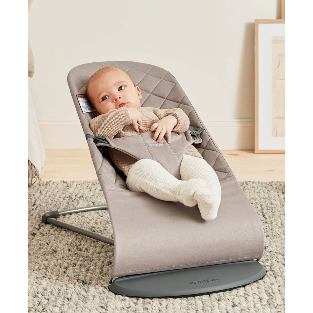 BabyBjorn Bouncer Bliss in gray fabric, baby lounging securely in the reclined seat on a sturdy base.