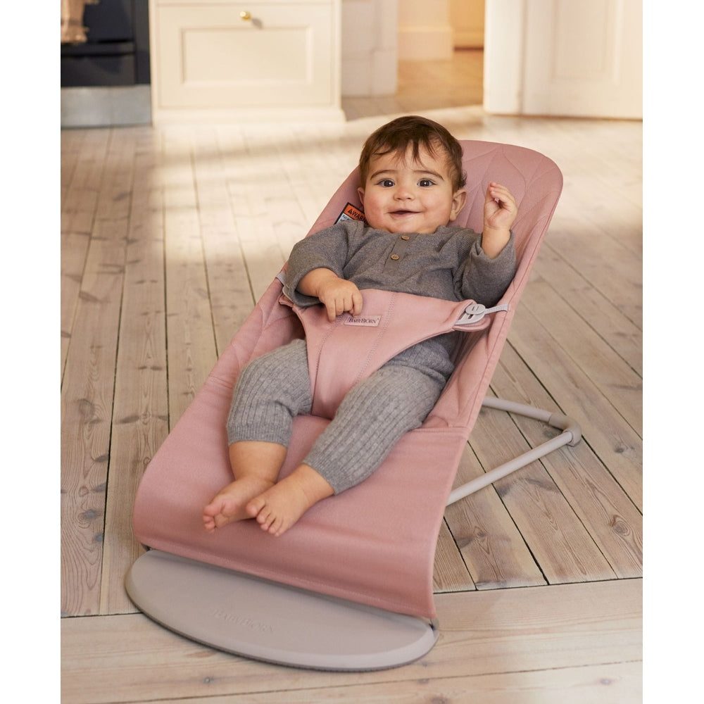 BabyBjorn Bouncer Bliss pink plush bouncer, baby in gray sits and gently bounces on the frame.