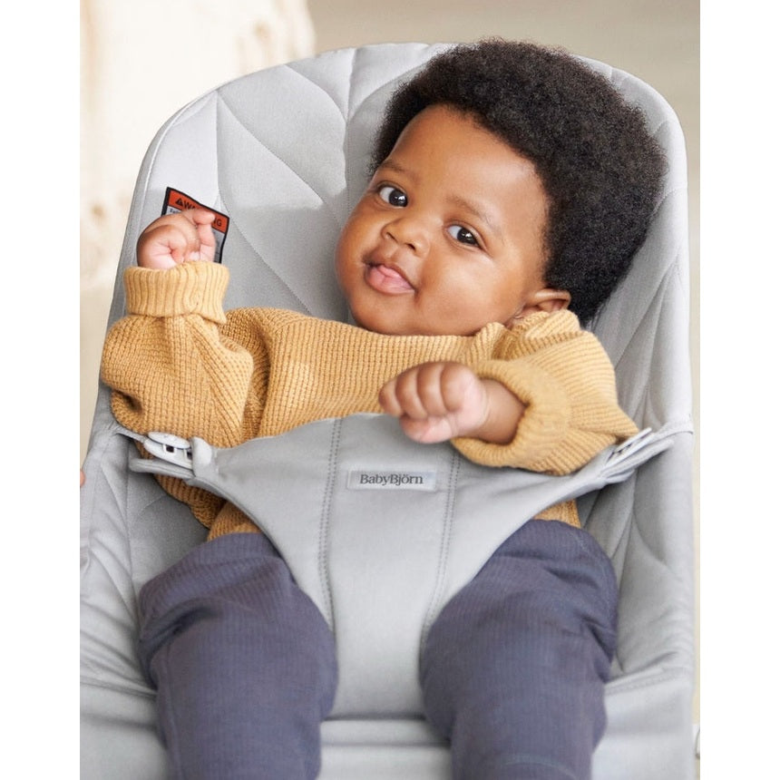 BabyBjorn Bouncer Bliss in gray; infant in mustard sweater sits settled, securely strapped in.