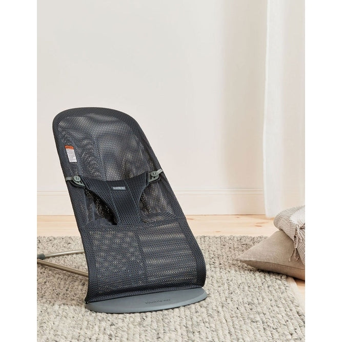 BabyBjorn Bouncer Bliss in black mesh with gray base, angled on a rug as a baby rocker.