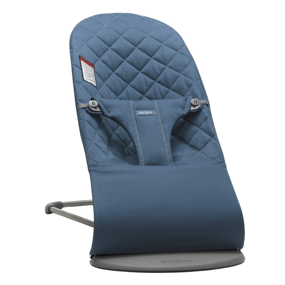 BabyBjorn Bouncer Bliss in blue quilted fabric, with secured harness, resting on a round gray base.