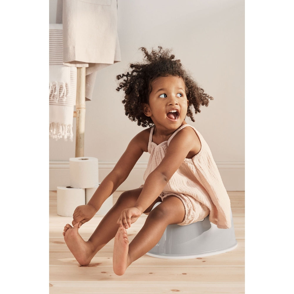 BabyBjorn Smart Potty in gray, with a joyful toddler seated on it in a soft neutral nursery.