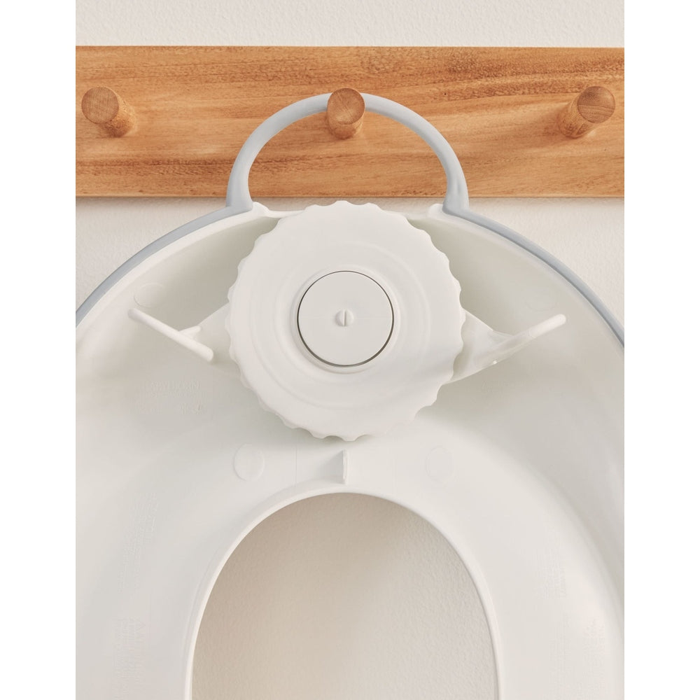 BABY BJORN Toilet Trainer white with adjustable dial, shown fitted to a toilet seat for secure training.