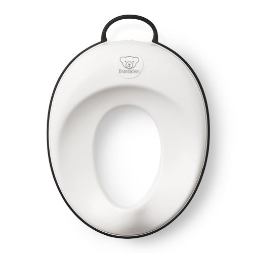 BabyBjorn Toilet Trainer in white with black edge, featuring a top handle for easy carrying.