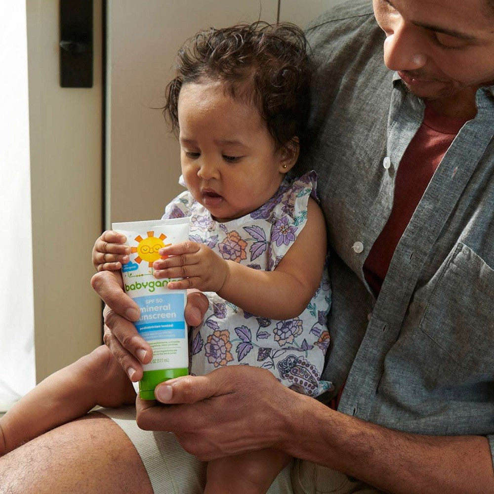 Babyganics Mineral Sunscreen Lotion SPF50 89 ml held by a baby and caregiver