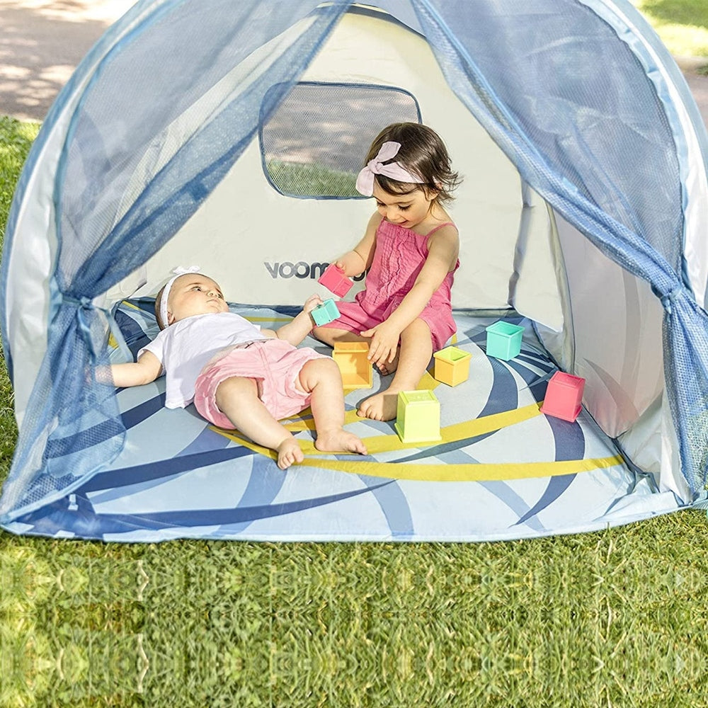 Babymoov Anti-UV Tropical Pop Up Tent; blue canopy, two kids playing with colorful blocks on grass