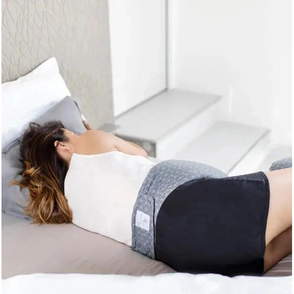 Babymoov Dream Belt Pregnancy Belt Sleep Solution in gray patterned fabric worn by a pregnant woman lying in bed for sleep support.