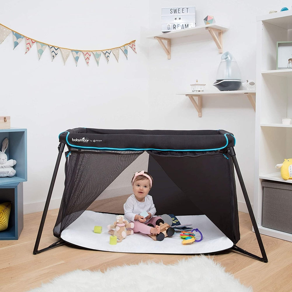 Babymoov Naos Travel Crib & Playard in black with mesh sides and turquoise trim, baby inside