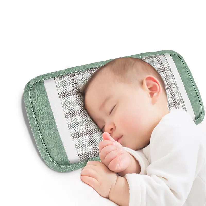 BC Babycare Armrest Summer Cushion in green with plaid gray center, baby peacefully sleeping on it.