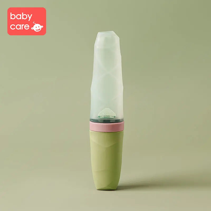 BC Babycare Feeding Spoon Dispenser in pastel green with pink band and translucent cap, standing upright.