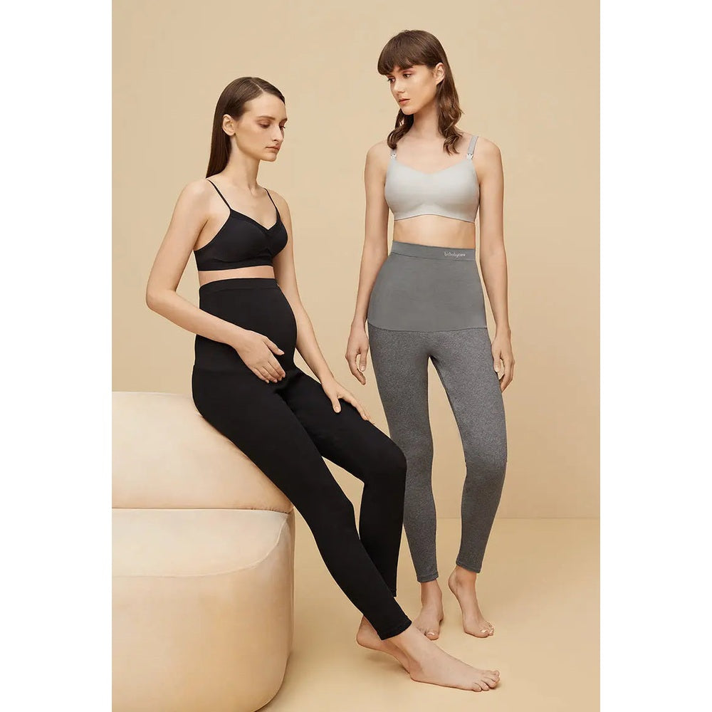 BC Babycare Maternity Leggings Black; two models wear high-waist full-length leggings, one seated cradling her belly.
