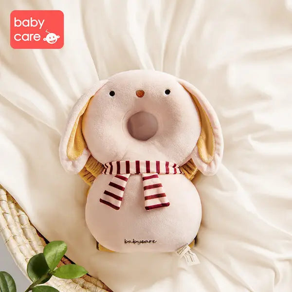Bc Babycare Protective Cushion plush dog on white bedding, cream with a red-striped scarf, showcasing soft safety comfort.
