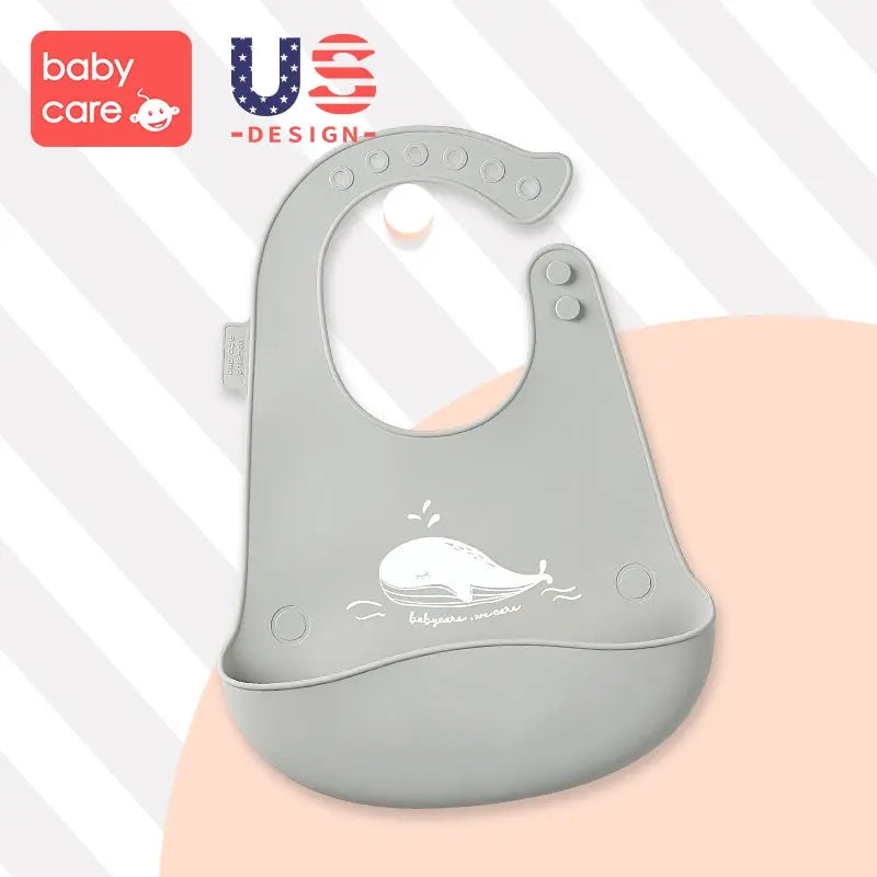 BC Babycare Silicone Adjustable Bib in gray with whale graphic; adjustable strap with snaps and spill-catching pocket.