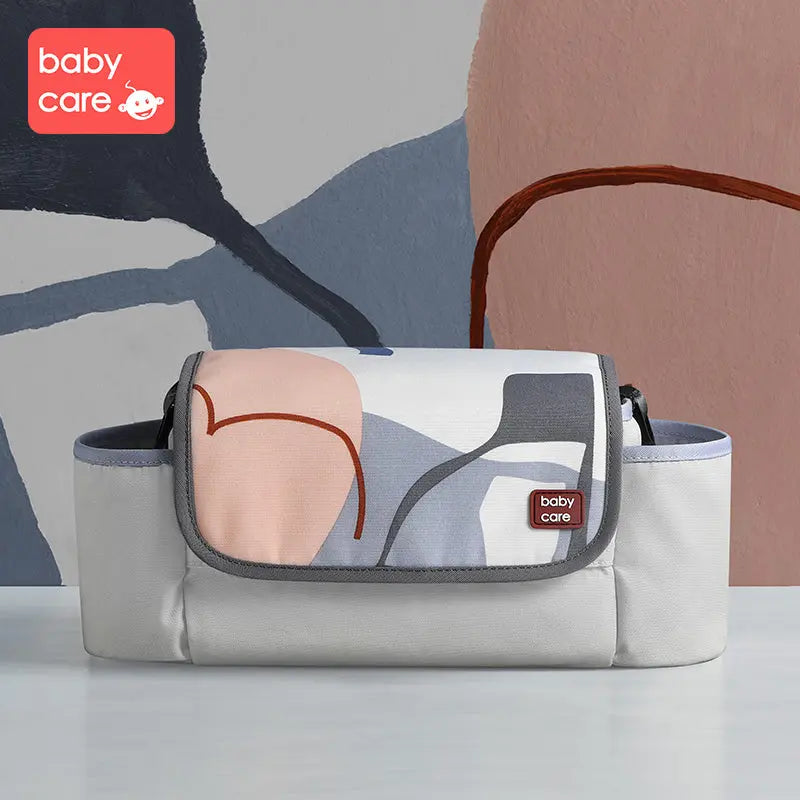 BC Babycare Stroller Organizer in gray with pastel abstract print; front flap with gray trim and red logo badge visible.