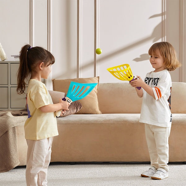 BC Babycare Toss & Catch Ball Set with blue and yellow scoops and a green ball, two kids play indoors