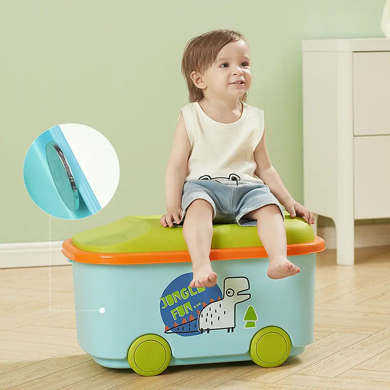 BC Babycare Toy Storage Box blue body with lime lid and green wheels; toddler sits on it, showing portable storage.