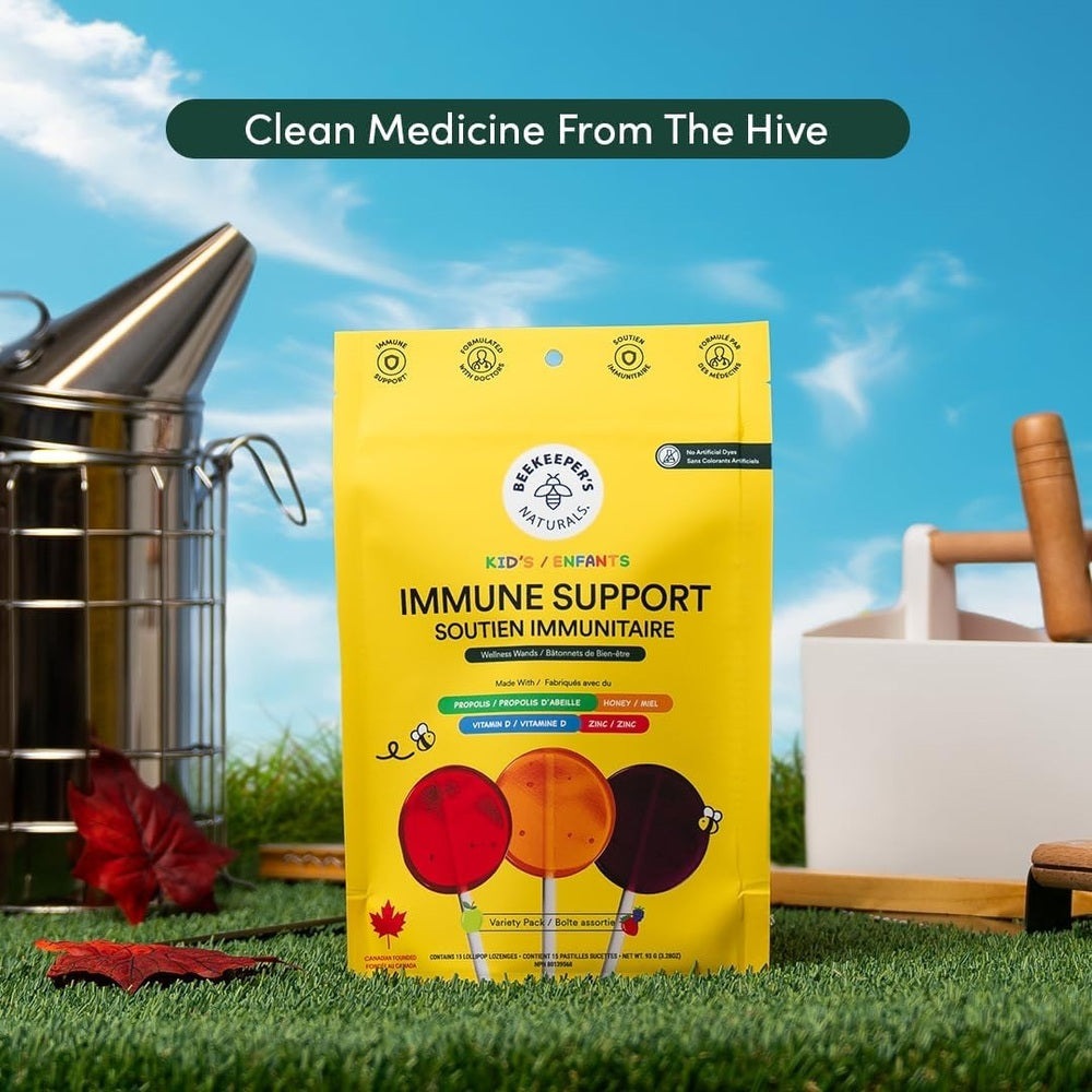 Beekeeper's Naturals Kid's Immune Support Wellness Wands Variety Pack 15 ct yellow pouch standing upright on grass in sunny outdoor scene.