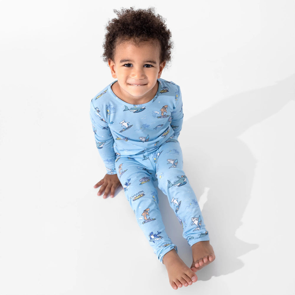Bellabu Bear Bamboo Kids Pajamas Shark School in blue with shark print, child sits on white floor.